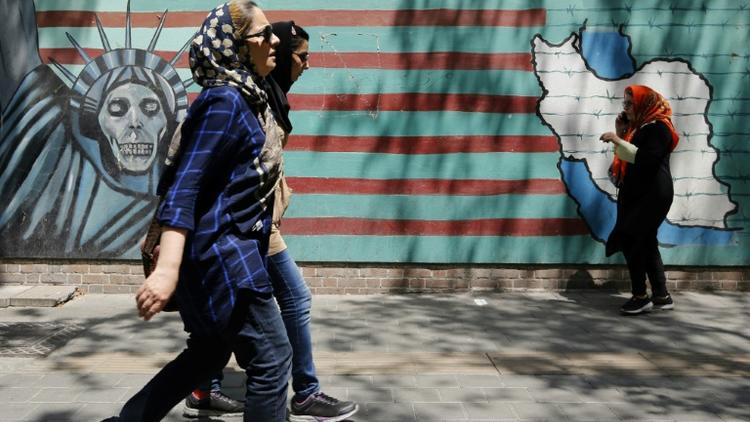 Des Iraniennes passent devant la façade de l'ancienne ambassade des Etats-Unis à Téhéran le 7 août 2018. [ATTA KENARE / AFP]