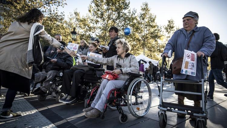 Des militants distribuent leurs revendications devant une station de métro à Paris, lors d'une manifestation de l'association APF France Handicap, le 26 septembre 2018 [Philippe LOPEZ / AFP]