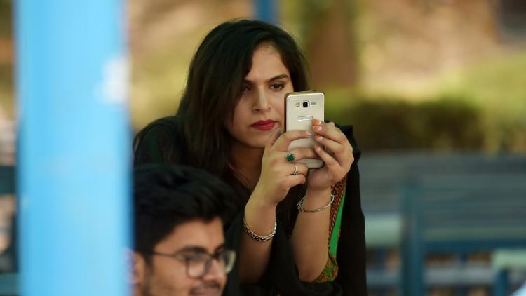 Une étudiante utilise un smartphone sur le campus d'Islamabad le 12 juillet 2018 [Aamir QURESHI / AFP]