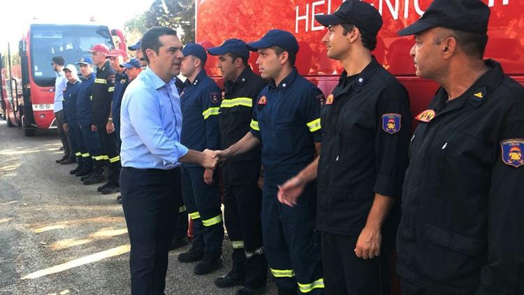 Le Premier ministre grec Alexis Tsipras (c) salue les pompiers ayant combattu les incendies meurtriers de Mati, à l'est d'Athènes, le 30 juillet 2018 [- / GREEK PRIME MINISTER'S PRESS OFFICE/AFP/Archives]