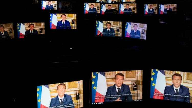 Emmanuel Macron sur des écrans de tablette alors qu'il parle depuis l'Elysée lors d'une allocution télévisée, le 13 avril 2020 à Paris [Martin BUREAU / AFP]