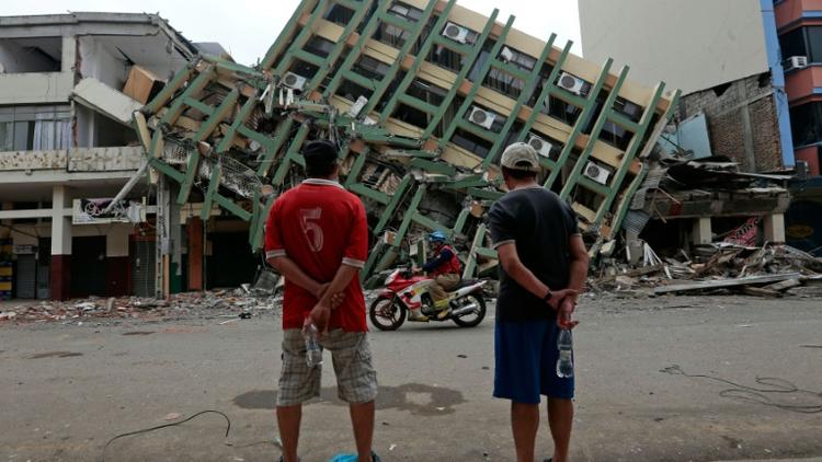 Deux hommes regardent un immeuble détruit à Portoviejo, en Equateur, le 21 avril 2016, une semaine après le violent séisme qui a ravagé le pays [Juan Cevallos / AFP]