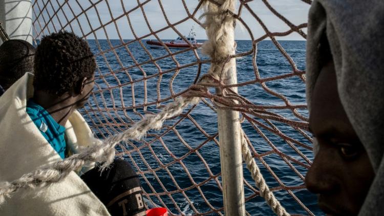 Des migrants à bord du Sea Watch 3 observent un bateau des garde-côtes italiens [FEDERICO SCOPPA / AFP]