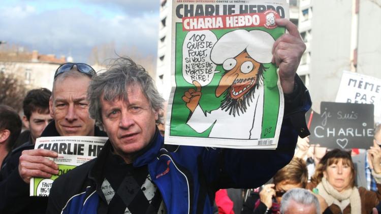 Des manifestants lors de la marche républicaine du 11 janvier 2015 à Paris brandissent des exemplaires du dernier Charlie Hebdo [RAYMOND ROIG / AFP]