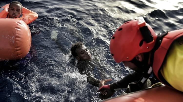 Un sauveteur de l'ONG Proactiva Open Arms aide un migrant à sortir de l'eau, le 3 octobre 2016 au large des côtes libyennes [ARIS MESSINIS / AFP/Archives]