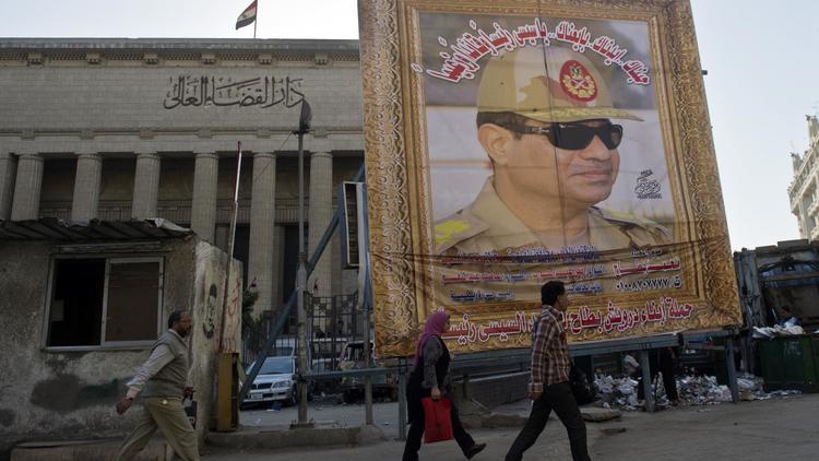 Des Egyptiens marchent devant un immense portrait du général Al-Sissi au Caire, le 27 mars 2014 [Khaled Desouki / AFP/Archives]