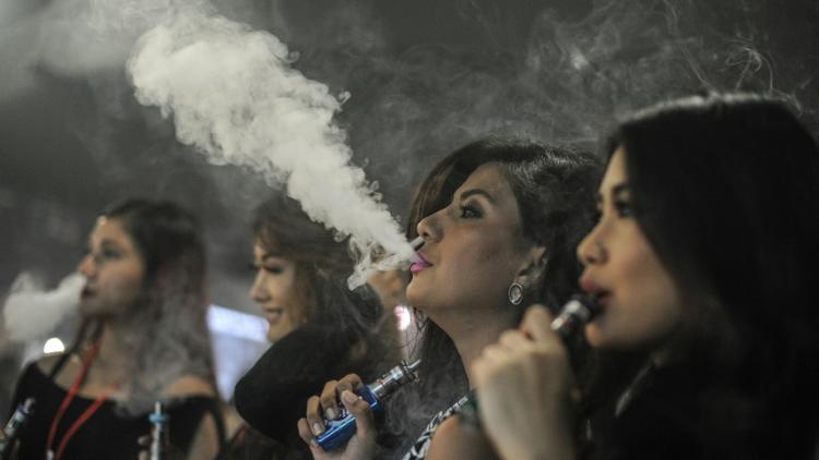 Des personnes fument des cigarettes électroniques pendant la VapeFair à Kuala Lumpur, le 5 décembre 2015 [MOHD RASFAN / AFP/Archives]