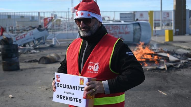 Un militant CGT porte une cagnotte pour les grévistes, lors d'un repas de noël organisé le 24 décembre 2019 au port de Marseille [Christophe SIMON / AFP]