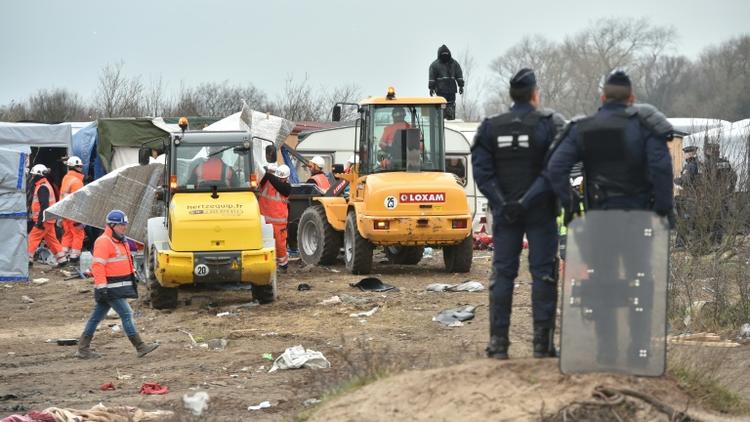 Des policiers surveillent le démantèlement d'abris dans la "jungle" de Calais par des bulldozers, le 1er mars 2016 [PHILIPPE HUGUEN / AFP]