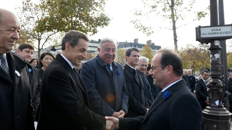 Poignée de mains entre François Hollande (D) et Nicolas Sarkozy, en présence de Jean-Yves Le Drian, Gérard Larcher, Manuel Valls et Claude Bartolone lors de la commémoration de l'amistrice, le 11 novembre 2015 sur les Champs Elysées à Paris [ERIC FEFERBERG / POOL/AFP]