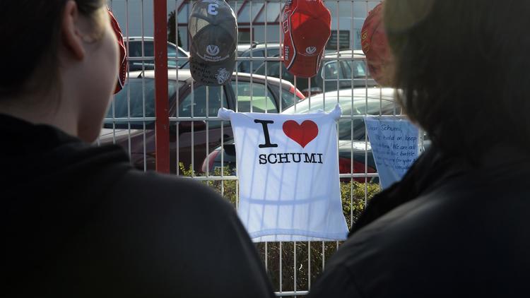 Des fans regardent, le 3 janvier 2014, des messages de soutien à Michael Schumacher, déposés sur les grilles du circuit de karting qu'il possède, à Kerpen [Patrik Stollarz / AFP/Archives]