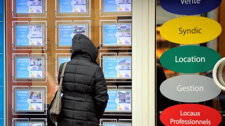 Une femme regarde les annonces dans la vitrine d'une agence immobilière [Philippe Huguen / AFP/Archives]