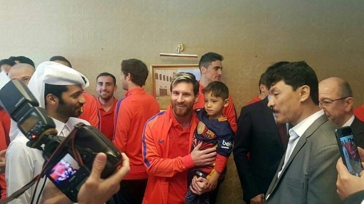 L'attaquant argentin du FC Barcelone Lionel Messi (C) tient dans ses bras le jeune Afghan Murtaza Ahmadi, le 13 décembre 2016 à Doha [STRINGER / Qatar’s Supreme Committee for Delivery and Legacy/AFP]