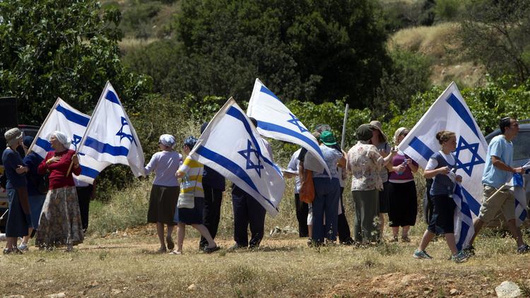 Des colons agitent le drapeau de l'Etat hébreu près du village arabe de Al-Khader en Cisjordanie, le 24 mai 2013 [Ahmad Gharabli / AFP/Archives]
