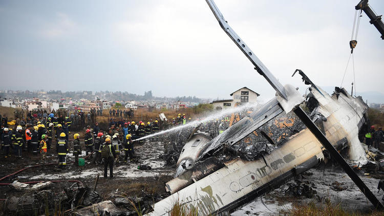 Des secours népalais rassemblés autour de la carcasse d'avion fumante, le 12 mars dernier. 