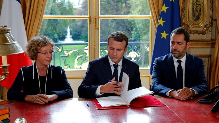Emmanuel Macron, aux côtés de Muriel Penicaud et Christophe Castaner signe les ordonnances réformant le droit du travail, le 22 septembre 2017 à l'Elysée [PHILIPPE WOJAZER / POOL/AFP/Archives]