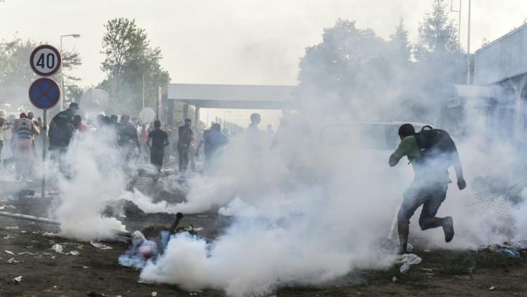 Des réfugiés courent pour se protéger des gaz lacrymogènes à la frontière serbo-croate près de la ville de Horgos, le 16 septembre 2015 [ARMEND NIMANI / AFP]