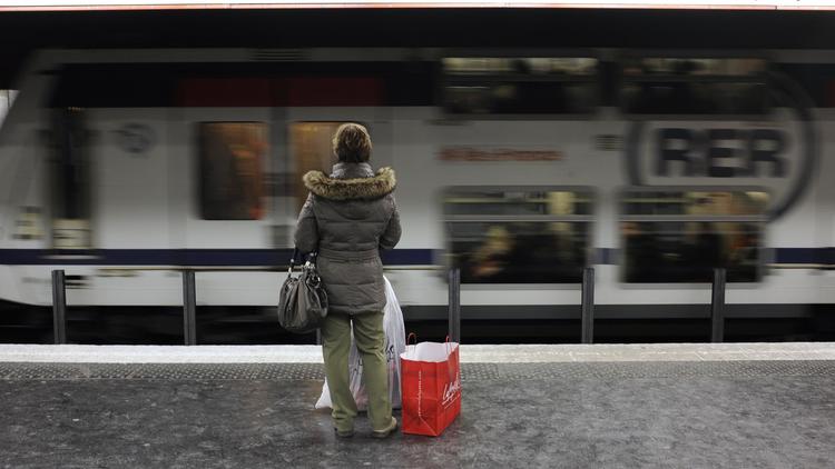 Une femme attend un RER à Paris [Fred Dufour / AFP/Archives]
