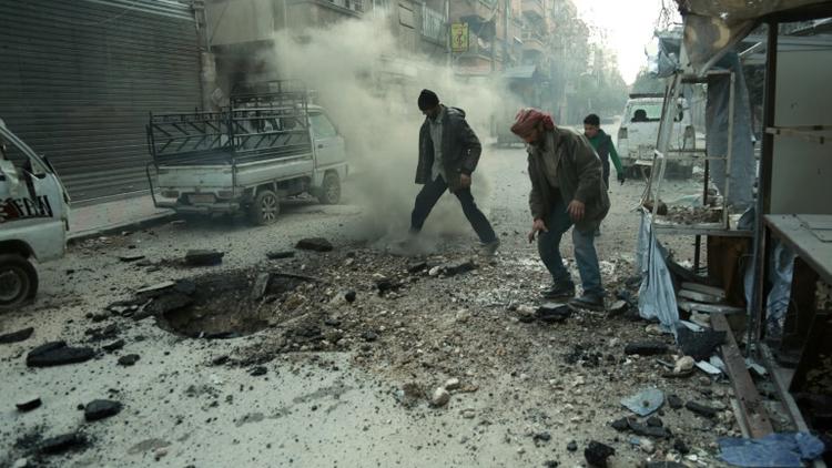 Des hommes constatent les dégâts après un bombardement du régime sur Douma, la principale ville de l'enclave rebelle dans la Ghouta orientae, le 10 mars 2018 [HAMZA AL-AJWEH / AFP]