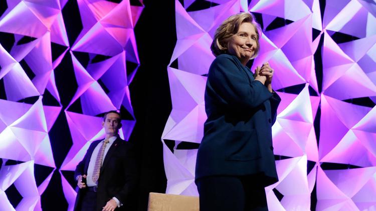 L'ancienne secrétaire d'Etat américaine Hillary Clinton réagit après qu'une femme a lancé une chaussure en sa direction pendant une conférence, tandis qu'un agent de sécurité (derrière elle) s'apprête à la protéger, le 10 avril 2014 à Las Vegas [Isaac Brekken / Getty/AFP]
