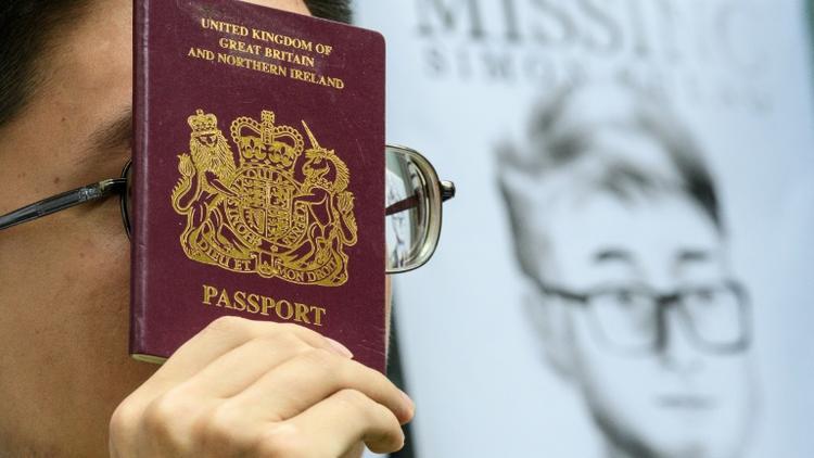 Un militant brandit un passeport britannique devant un portrait de Simon Cheng, le 21 août 2019 devant le consulat de Grande-Bretagne à Hong Kong [Anthony WALLACE / AFP/Archives]