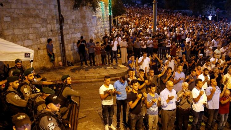 Des forces de sécurité israéliennes regardent des Palestiniens prier à l'extérieur de l'esplanade des Mosquées à Jérusalem, le 24 juillet 2017 [Ahmad GHARABLI / AFP]