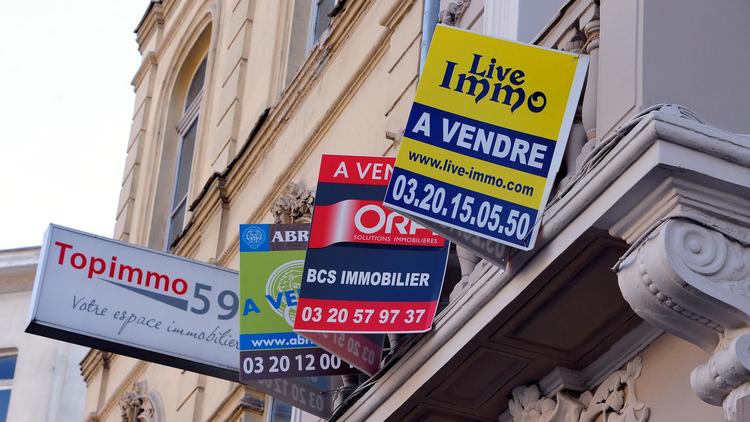 Des panneaux d'agences immobilières sur la façade d'un immeuble où un appartement est à vendre [Philippe Huguen / AFP/Archives]