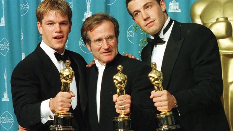 Les acteurs et scénaristes Matt Damon (gauche) et Ben Affleck (droite) posent avec Robin Williams (centre) et leurs Oscars pour "Will Hunting" le 23 mars 1998 à Los Angeles [Hal Garb / AFP/Archives]