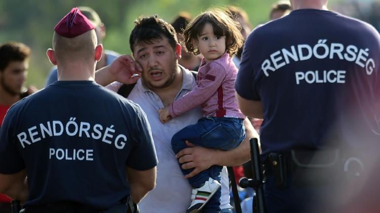 Bloqué par des policiers hongrois,un migrant essuie ses larmes le 14 septembre 2015 près de Roszke à la frontière entre la Hongrie et la Serbie [ATTILA KISBENEDEK / AFP]