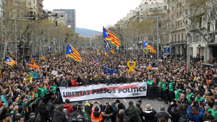 Manifestants devant les bureaux de la Commission européenne à Barcelone le 25 mars 2018 pour protester contre l'arrestation de Carles Puigdemont en Allemagne, à la demande de la justice espagnole. Il est écrit "Liberté pour prisonniers politiques" sur la banderole. [LLUIS GENE / AFP]