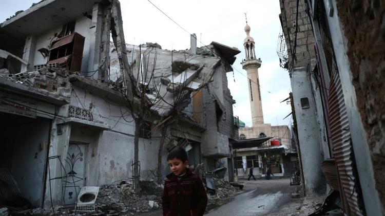 Un enfant marche dans une rue bordée de maisons détruites, le 9 janvier 2017 à Douma, près de Damas, en Syrie [Abd Doumany / AFP]
