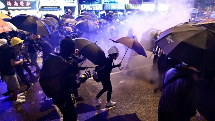 Des manifestants tentent de se protéger des nuages de gaz lacrymogène, le 28 juillet 2019 à Hong Kong [Anthony WALLACE / AFP/Archives]