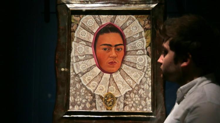 Un employé du musée Victoria & Albert Museum de Londres devant un autoportrait de Frida Kahlo lors d'une exposition consacrée à l'artiste mexicaine, le 13 juin 2018 [Daniel LEAL-OLIVAS / AFP]