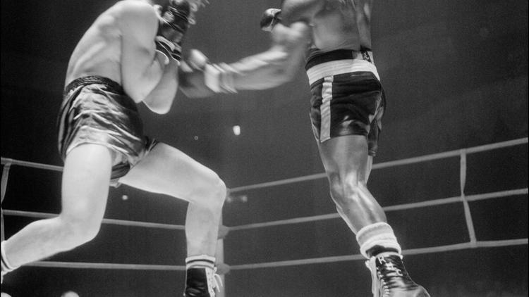 L'Italien Fabio Bettini (G) met un genou à terre face à l'Américain Rubin Carter, le 23 février 1965 au palais des sports à Paris, lors d'un combat international de boxe dans la catégorie des poids moyens  [ / Pool/AFP/Archives]