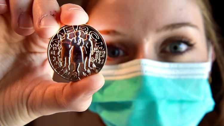 Un membre du personnel soignant montre la médaille créée par la Monnaie de Paris, en hommage aux corps médical, éboueurs, caissiers, agriculteurs etc., le 15 mai 2020 à Pessac, en Gironde [GEORGES GOBET / AFP]