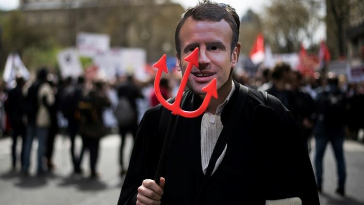 Un manifestant portant un masque à l'effigie d'Emmanuel Macron défile avec des avocats, des magistrats et des greffiers à Paris le 11 avril 2018, contre le projet de réforme de la justice [Lionel BONAVENTURE / AFP]