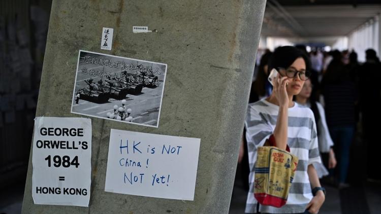 Des affichettes dénonçant le projet de loi visant à autoriser les extraditions vers la Chine sont collées sur un mur près du Conseil législatif à Hong Kong, le 14 juin 2019 [Hector RETAMAL / AFP]
