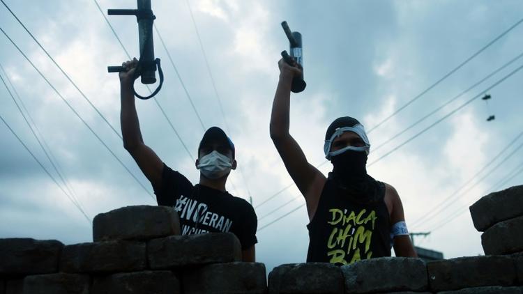 Des manifestants contre le gouvernement brandissent leurs armes artisanales derrière une barricade à Managua, le 20 juin 2018 [MARVIN RECINOS / AFP]