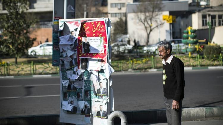 Un homme se tient à côté d'affiches électorales à Téhéran, capitale de l'Iran, le 25 février 2016  [BEHROUZ MEHRI / AFP]