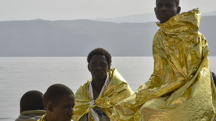 Des migrants dans des couvertures de survie après avoir été secouru au large des côtes italiennes.