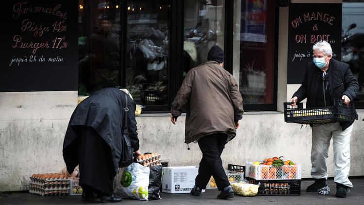 Des gens ramassent l'excédent de nourriture devant un restaurant à Paris, le 16 mars 2020, car tous les lieux publics non essentiels, y compris les restaurants et les cafés, ont été fermés pour contenir la propagation du nouveau coronavirus. 